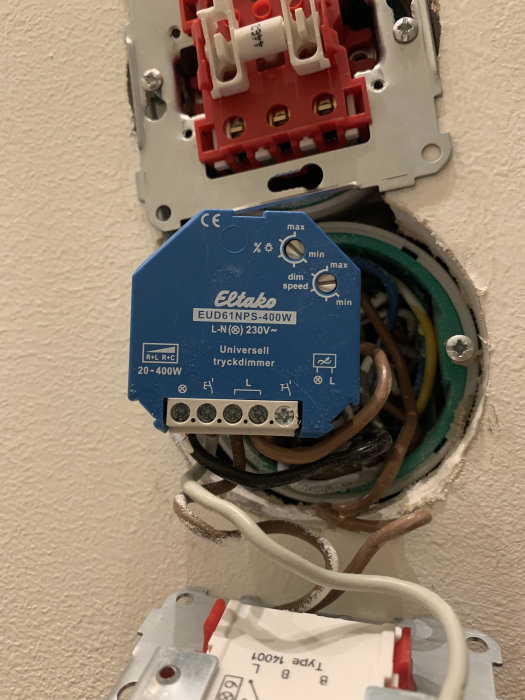 Elko återfjädrande knapp och Eltako universaldimmer utan nolla i en öppen elinstallation.