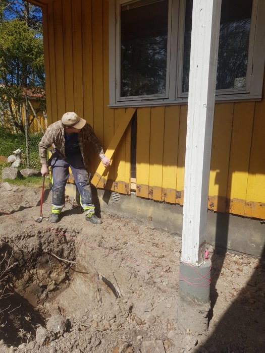 Person gräver vid husgrund där en veranda tagits bort för en utbyggnad.