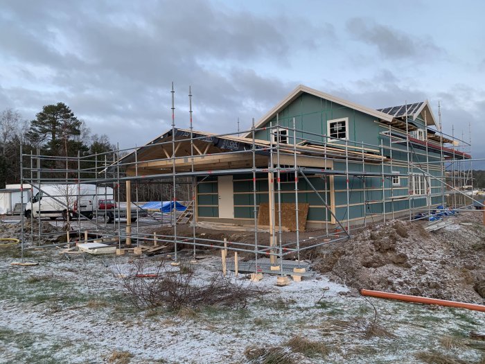 Scaffolding surrounding a house under construction with a temporary door installed in the garage.