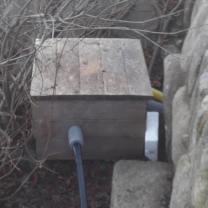 Träkapsling med slangar och tätningar utomhus använd för att skydda termostat, visar tecken på kondens.