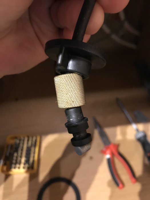 Närbild på en defekt plastgänghylsa och vajer till en lyftventil för diskbänk.