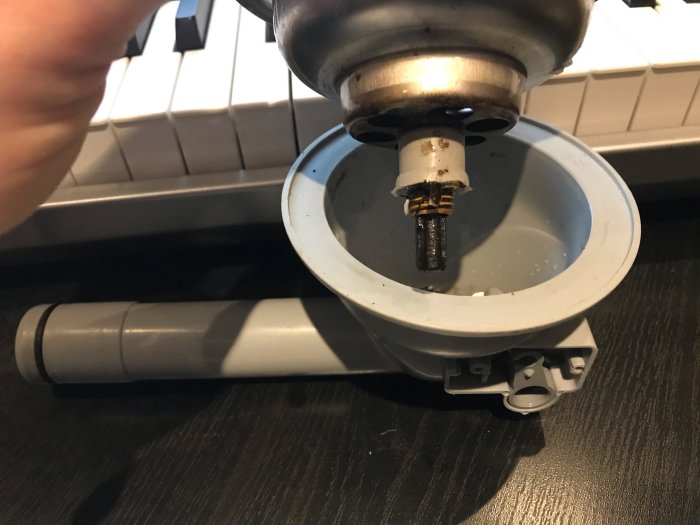 Närbild på trasig plastgänghylsa och lyftventil i ett diskbänksavlopp.