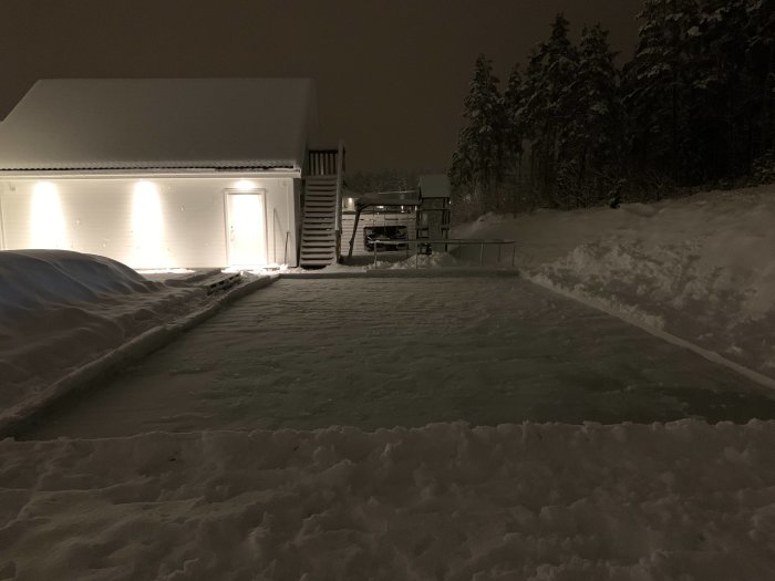 Isbana byggd av vit press och överblivet virke utanför ett hus på kvällen.