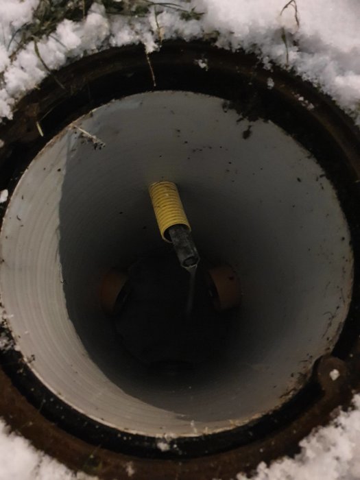 Dagvattenbrunn med pump och överlopp i snötäckt miljö.