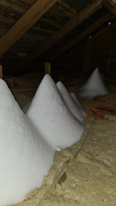 Tre stora snöhögar på vinden som kommit in genom taket.