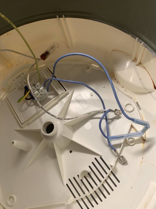 Öppen elinstallation med otillkopplade färgkodade sladdar och en demonterad vit plastkomponent mot grå bakgrund.