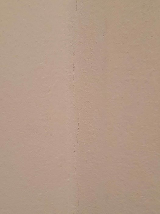 En nymålad vägg med en synlig spricka som löper vertikalt, vilket illustrerar problem med sprickbildning efter spackling.