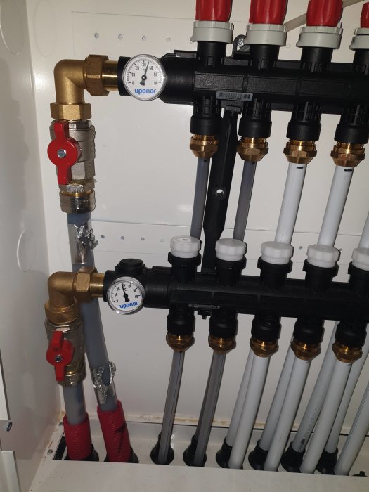 Installation av rörsystem med mätare och ventiler för värme i ett hem.