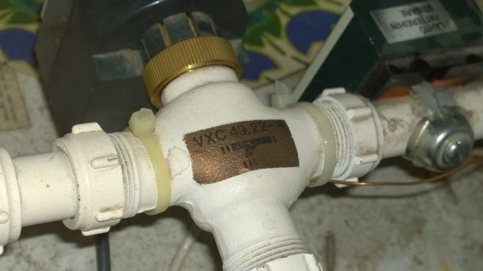 Närbild av en vit shuntventil i ett värmesystem märkt med 'VXC 49.22-4'.