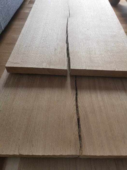 Två massiva ekplankor med en spricka i kanten på ett golv.