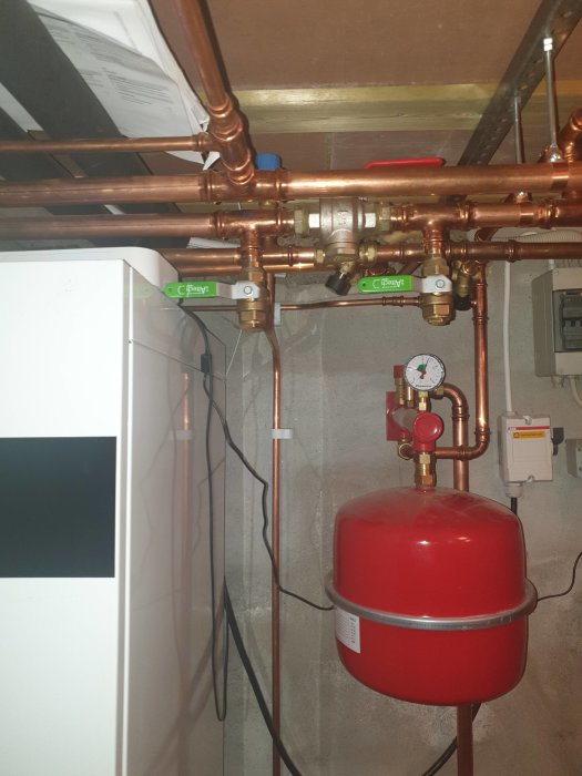Installation av uppvärmningssystem med kopparledningar, expansionskärl och mätare i ett pannrum.