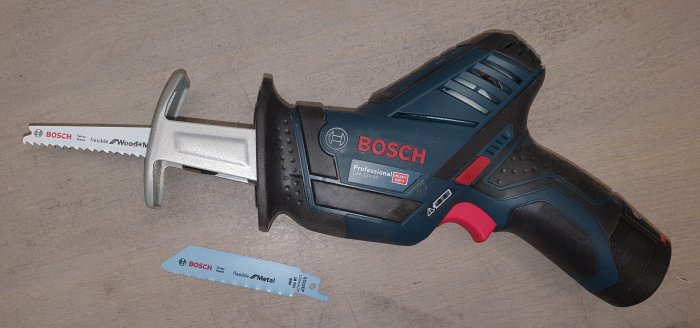 Bosch tigersåg med trä- och metallblad på träbord.