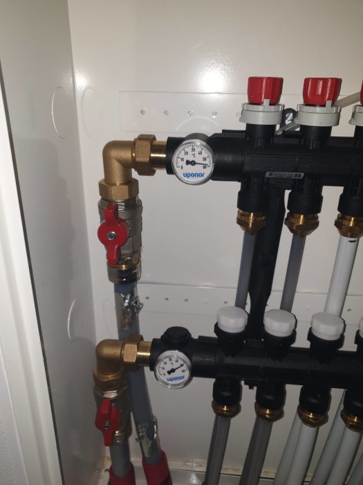Värmesystem med Uponor rör och termometrar på en vit vägg.