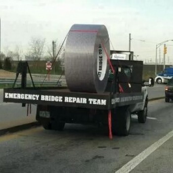 Lastbil med stor rulle silvertejp och texten "EMERGENCY BRIDGE REPAIR TEAM" på sidan.