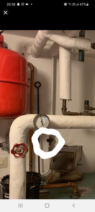 Värmesystem med rör, expansionskärl i rött, och en utringad påfyllningsventil.