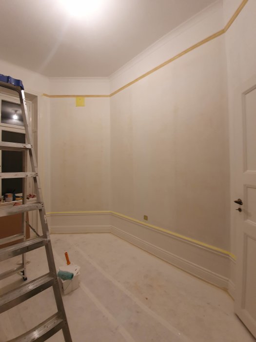 Renoverat rum med armeringsduk uppsatt på väggar, täckt golv och stege.
