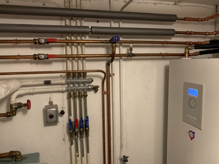Detaljerad bild på installation med rör och en väggmonterad värmepanna.