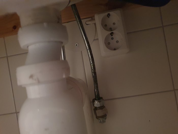 Eluttag och en kopplingsdosa placerade på ett osäkert sätt under ett tvättställ i ett badrum.