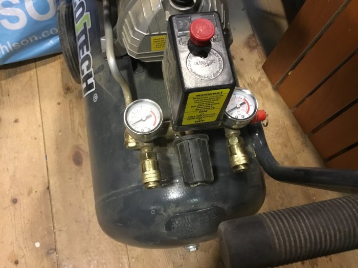 Begagnad Cotech kompressor 50l med två mätare och utgångsventiler på en verkstadsbänk.
