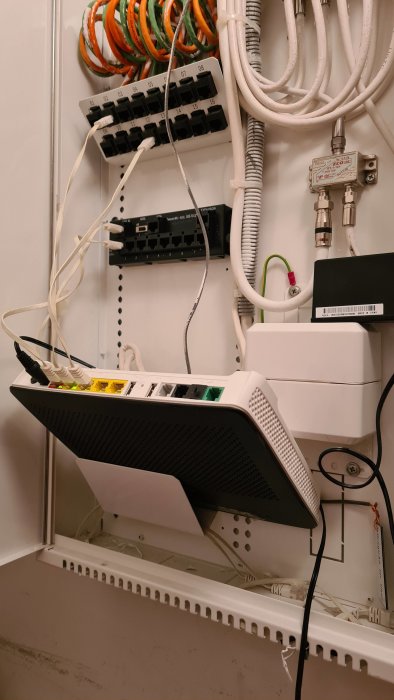 Nätverksskåp med Ethernet-patchpanel och en ansluten router för internetkabelanslutning.