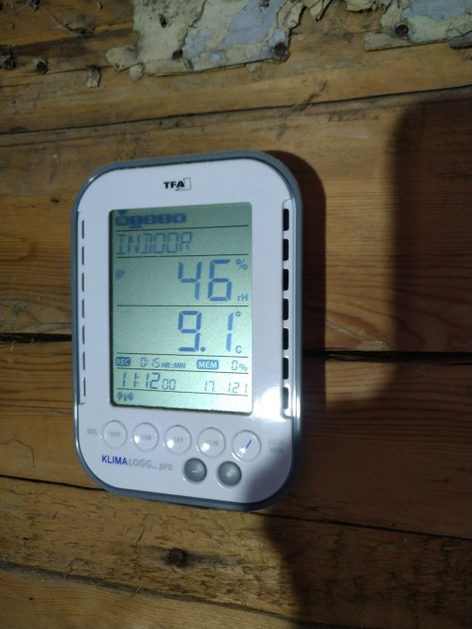 Hygrometer visar 46% luftfuktighet och 9.1°C temperatur på en trävägg under renovering.