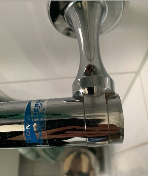 Närbild på kromad anslutning av handdukstork misstänkt för eldrift i badrum.