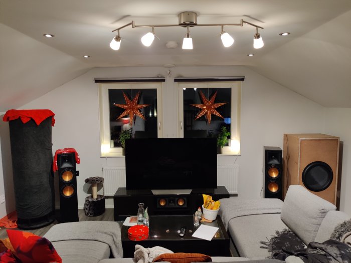 Vardagsrum med en nybyggd stor högtalare till höger och en mindre sonosub till vänster, framför TV och soffgrupp.