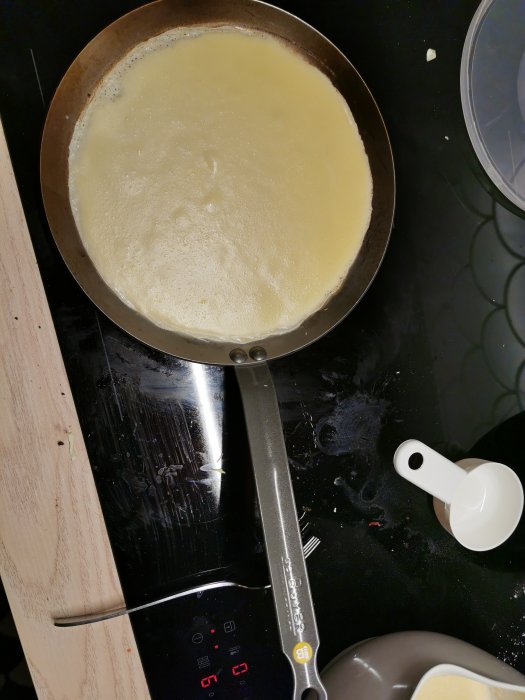 Pannkakssmet i en kolstålspanna på en spis, jämn värmefördelning syns.