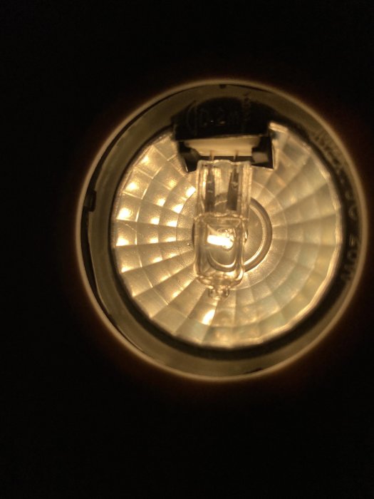Närbild av tänd halogenlampa med reflekterande armatur.