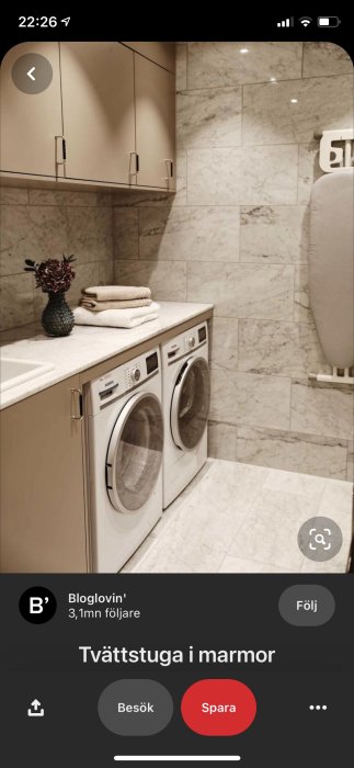 Tvättstuga med Miele tvättmaskin och torktumlare i marmorklätt utrymme, handdukar och dekoration ovanpå.