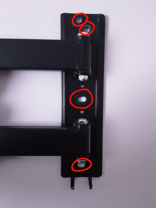 Väggfäste för TV med utmarkerade skruvhål för mollyplugg.