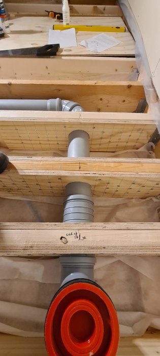 Installation av 21mm plywood i bjälklag med 110mm hål för rörledning, fastsatt med 6x60mm skruvar och trälim.