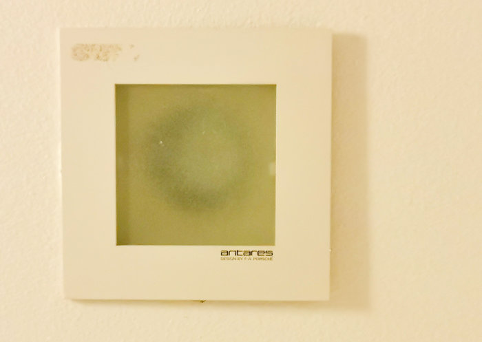 Inbyggd vit takarmatur märkt "antares DESIGN BY PORSCHE" i badrumstak med synligt märke.