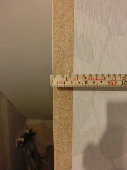 Måttband visar att endast 3 cm tapet behövs för att täcka väggens kant.