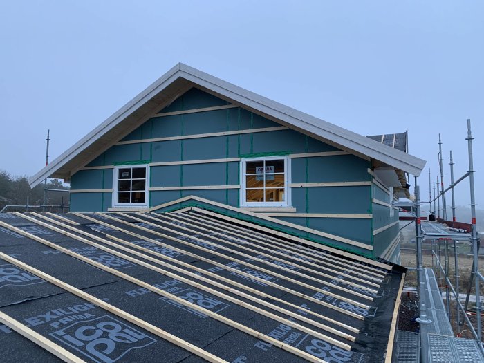 Hustak med luftspalt under konstruktion, snickrarbeten på gavel och vindskivor på carport syns.