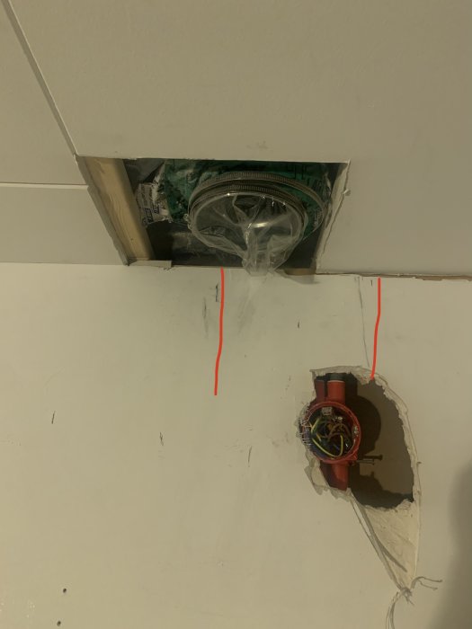 Öppet utrymme i tak med synlig elinstallation och två röda linjer markerar köksfläktens nya position.