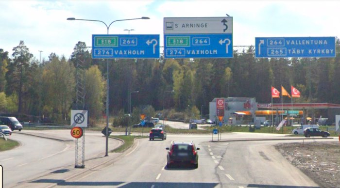 Vägskyltar över cirkulationsplats vid Kundvägen/Arningevägen med hastighetsgräns och biltrafik.