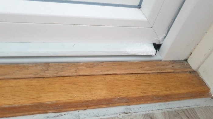Fukt och is på insidan av ett fönster med träkarm och synlig ventil.