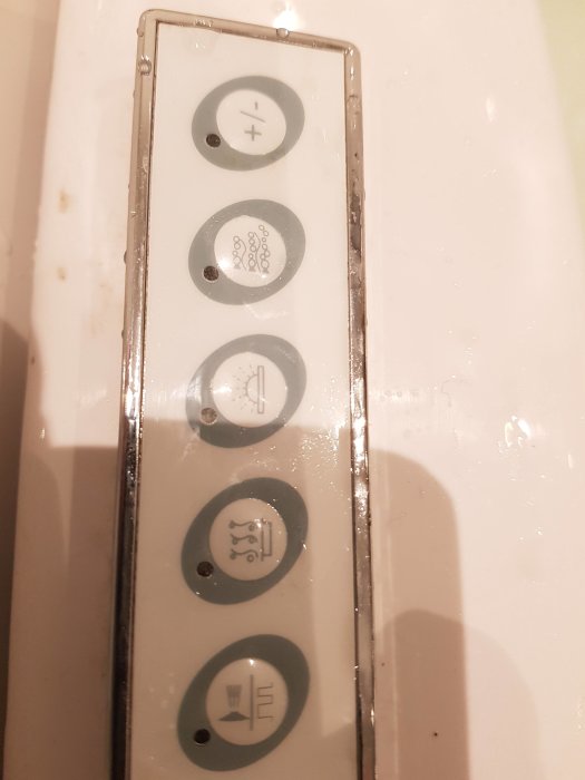 En panel med fyra knappar för kontroll av spabad, märkta med plus, bubblor, timer och värme-symboler.