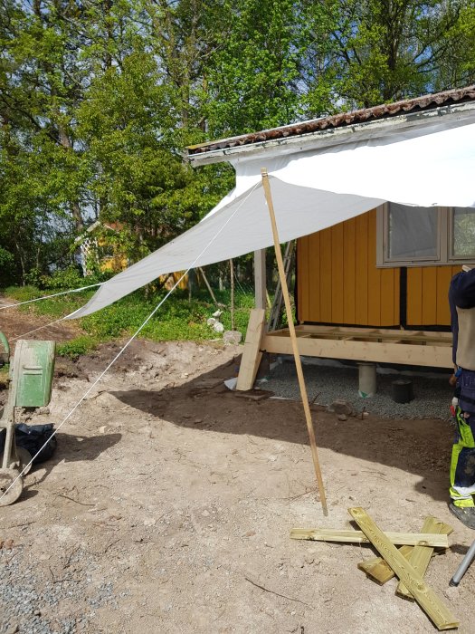 Presenningar uppsatta vid husutbyggnad för skydd mot ojämnt sommarväder.