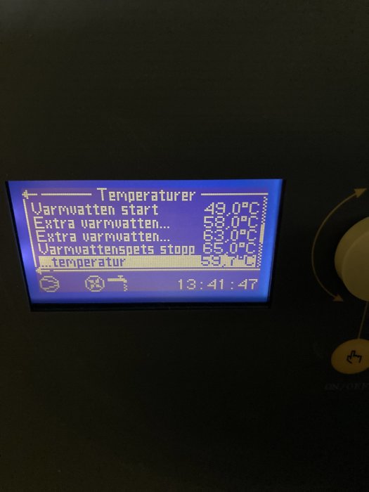 Digital display som visar temperaturinställningar för varmvatten i en uppvärmningsanläggning.