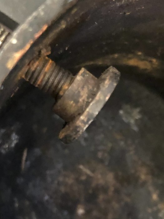 Närbild av en julgransfot med skruv och en fastklämd "stopp" i trästammen.