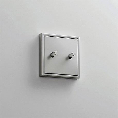 Jung LS1912 väggströmbrytare med en tvåknappsdesign monterad på en vit vägg.