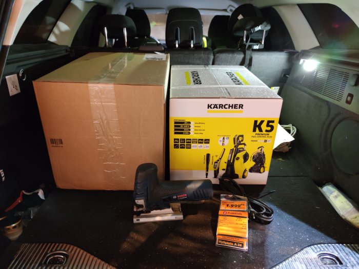 Kärcher K5 högtryckstvätt i låda och Bosch sticksåg GST 150 CE med prislapp i ett bagageutrymme.