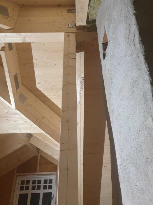 Nyinstallerad limträbalk stödd på trippla 220x45 reglar i en takkonstruktion med synlig isolering.