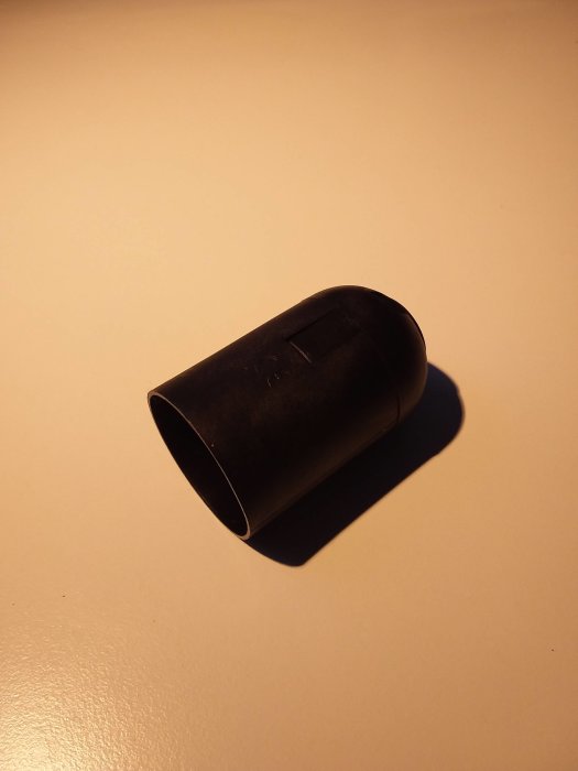 Stängd svart plasthållare för taklampa på ljus bakgrund, användare frågar om öppning utan våld.