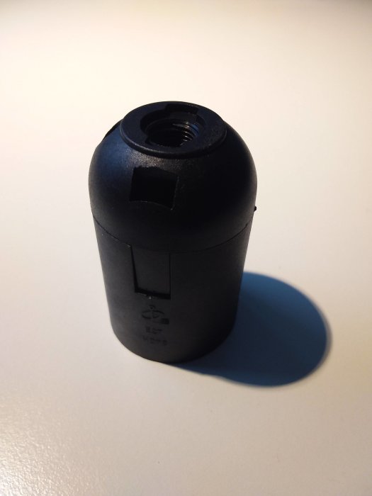 Stängd modern plastlampa sockel på vit yta, problem med att öppna för kabelfäste.