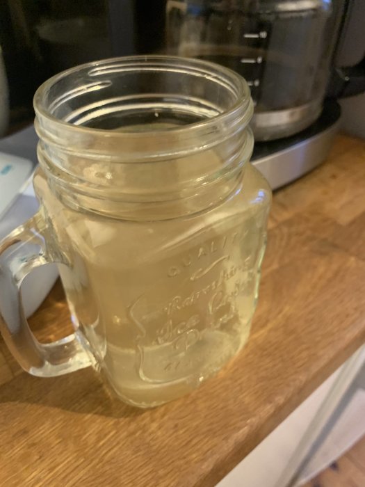 Ett glas med grumligt brunaktigt vatten på en träyta som antyder vattenkvalitetsproblem.