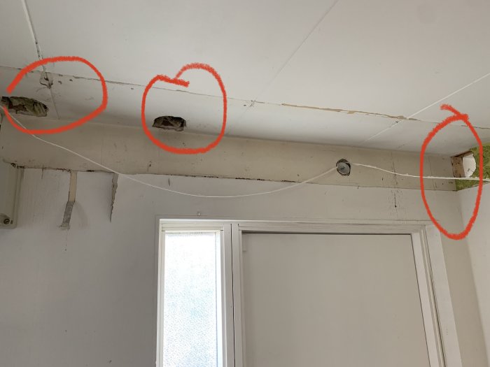 Takhörn i en hall med tre markerade hål efter borttaget rör, kabel hänger löst, behov av reparation.