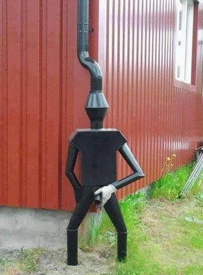 En kreativ skorsten i form av en figur som ser ut att gå med armar och ben mot en röd vägg.